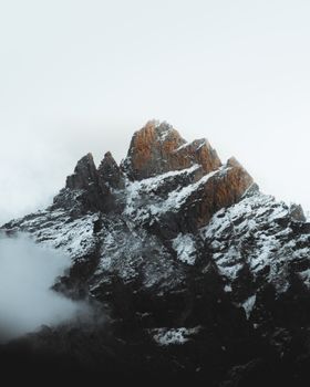 Dramatic illuminated mountain peak with snow and clouds at sunrise, showcasing nature's beauty. 10934861