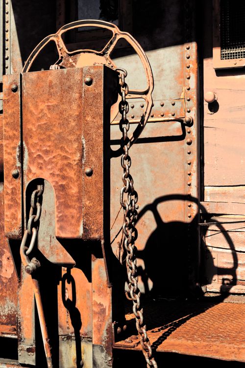 Free Close-up of a rusty chain and steering wheel with dramatic light and shadow in an industrial setting. Stock Photo