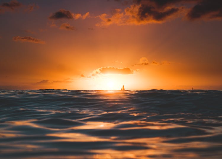 A Sailboat On The Horizon At Golden Hour