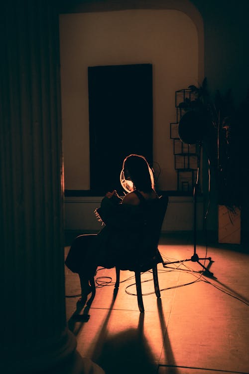 Silhouette of Woman Sitting on Chair on Stage