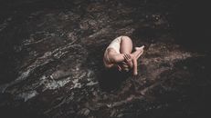 A Woman Curled Up on a Rough Surface