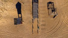 Wooden Walkway Between Wooden Structures on Sand