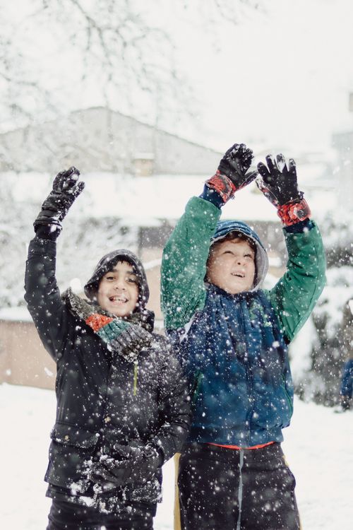 Free Two boys cheerfully playing in the snow during a snowy winter day, having fun outdoors. Stock Photo