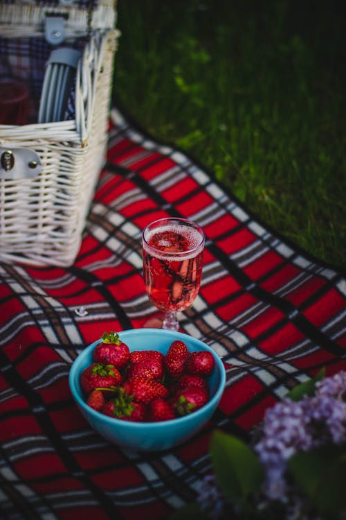 Gelas Anggur Bening Dengan Anggur Dekat Buah Strawberry Pada Tekstil Kotak Kotak Merah Putih Dan Hitam