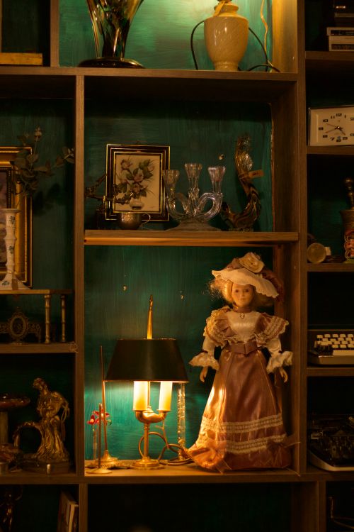 Free Elegant vintage shelf display with a decorative doll, lamp, and ornate decor items. Stock Photo
