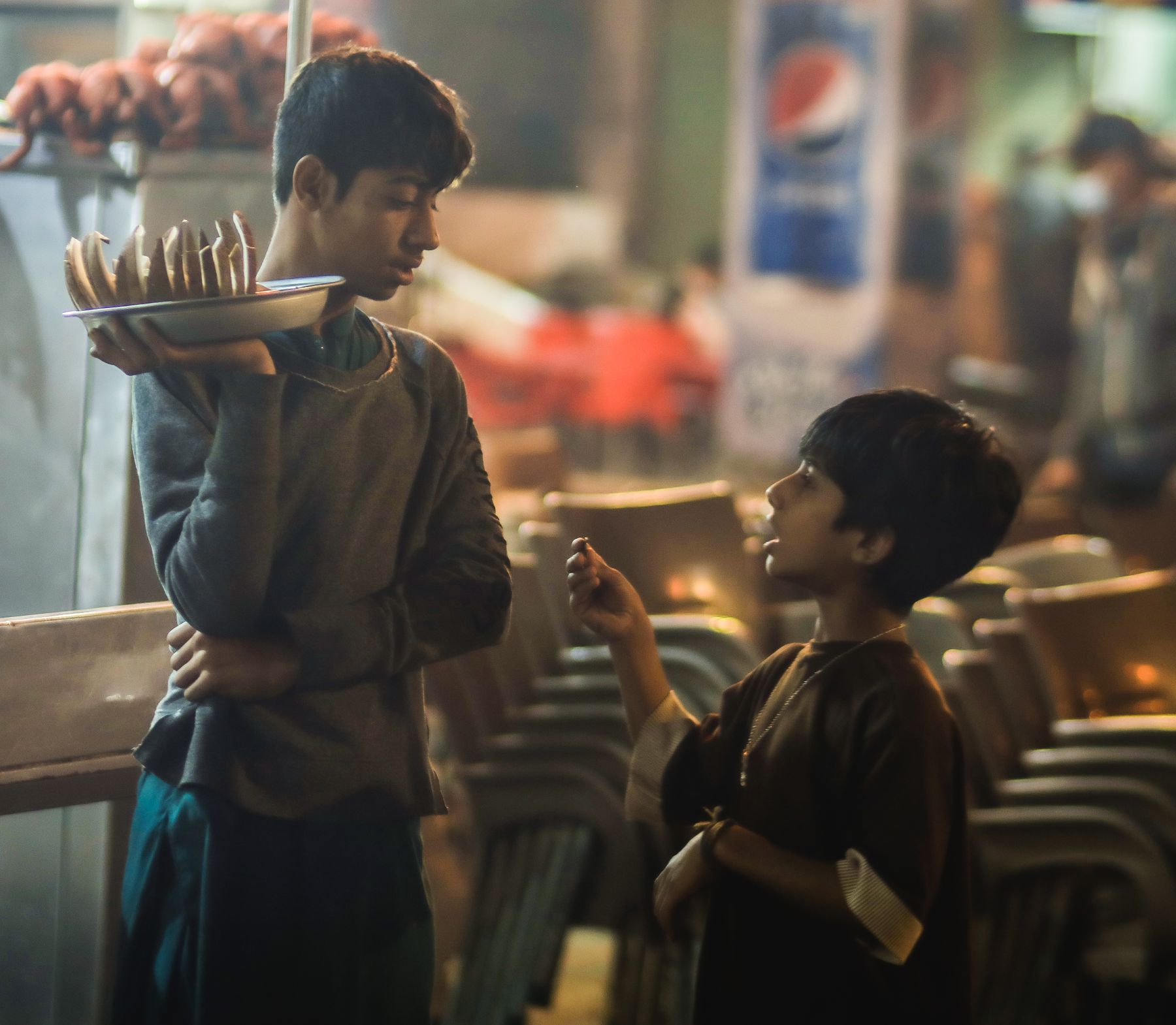 Two boys in conversation on a lively street in Karachi, highlighting cultural and urban life.