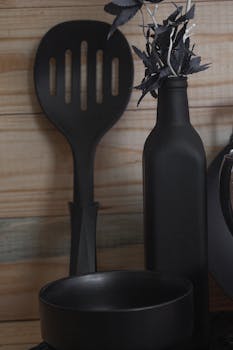 Elegant black kitchenware set against wooden background, showcasing minimalist design.