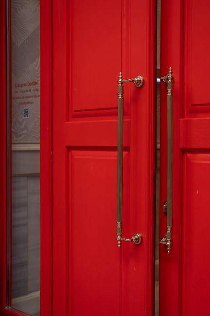 Close-up of a red double door featuring ornate metal handles, perfect for architectural themes.