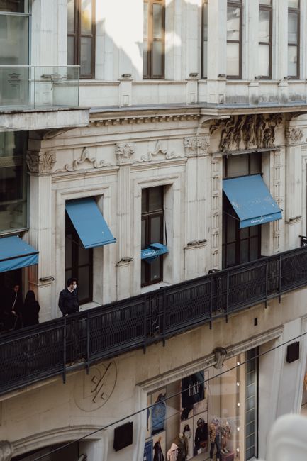 Elegant city building exterior featuring blue awnings and ornate architecture.