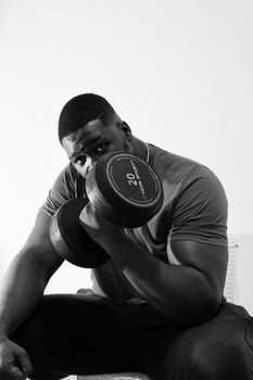 Black and white portrait of a man lifting a 20kg dumbbell, focusing on strength and fitness.
