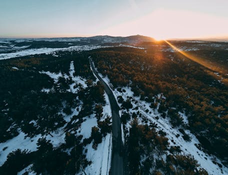 Drone shot capturing a snowy landscape with a winding road at sunrise in Karaağaç, Uşak, Turkey.
