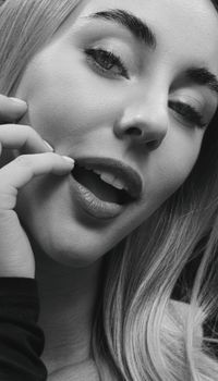 Close-up black and white portrait of a young woman with expressive eyes and subtle smile.