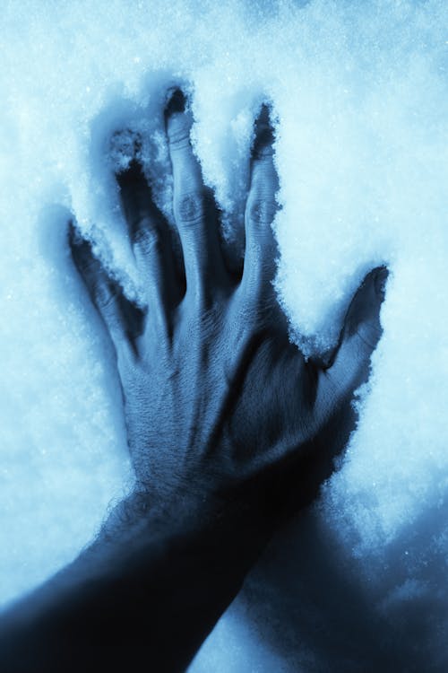 Close-Up Shot of a Person Touching the Freezing Snow