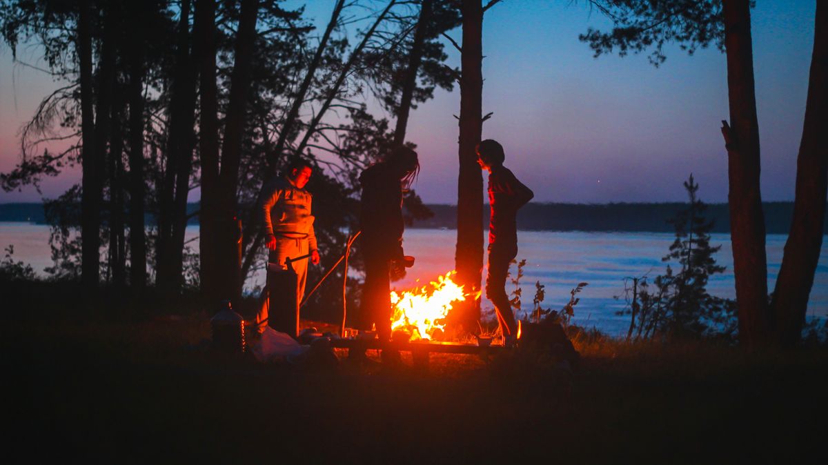 Silhouettes gathered around a campfire at dusk