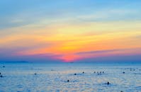 在热带海洋中，游泳者的剪影与五颜六色的日落共同营造出一片宁静的海滩景象