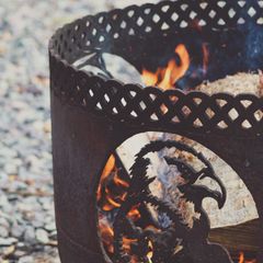 Flames behind the lattice cut-outs of a black steel fire pit