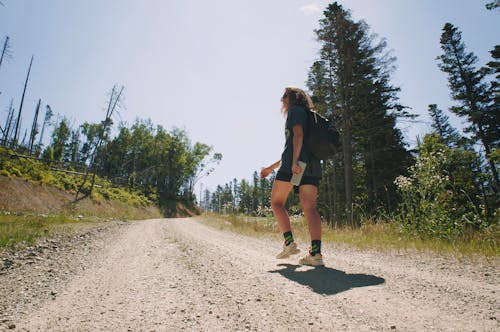 Low-Angle Shot of a Person Carrying a Back Pack while Walking on the Dirty Road