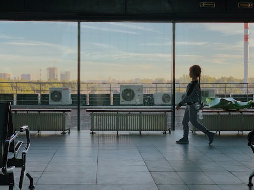 Girl in Airport Terminal Looking at Windows