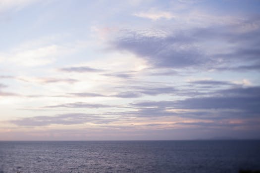 A tranquil ocean horizon view with soft pastel skies during sunset.