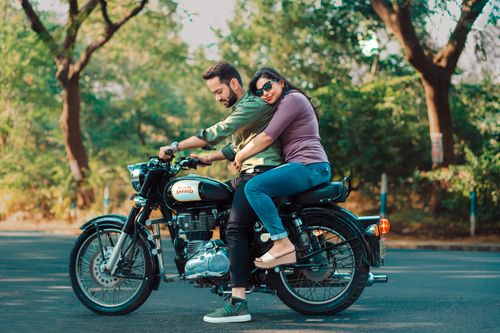 Free Happy couple riding a classic motorcycle through a lush green outdoor setting. Stock Photo