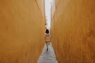 Back View of a Woman Walking in a Narrow Alley