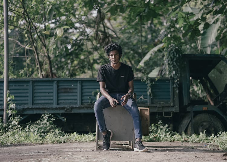 Man Sitting On Box In Front Of Truck