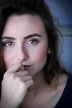 Closeup Photo of Woman in Black Top With Her Index Finger on Top of Her Lower Lip