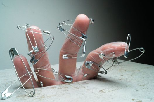 Close-up of a hand wearing glove with safety pins for a surreal artistic expression.
