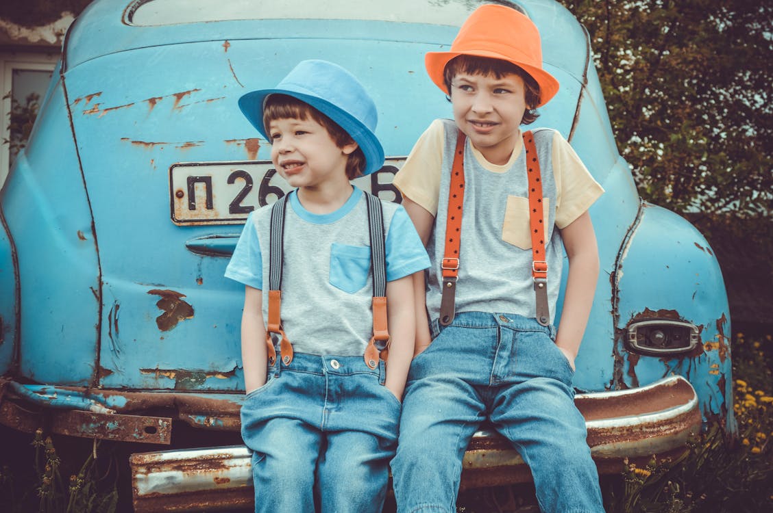免费 两个男孩坐在经典蓝色汽车的后保险杠上 素材图片