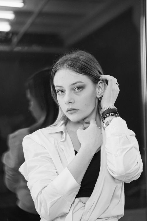 Free Stunning black and white portrait of a woman adjusting her hair, exuding elegance and grace. Stock Photo