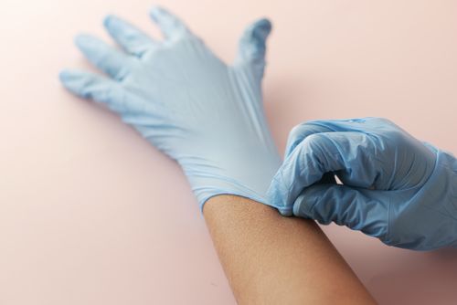 Free A close-up shot of a person wearing blue surgical gloves on a light background. Stock Photo