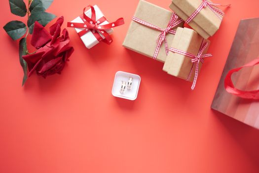 Delicate gift boxes, red roses, and a jewelry box set against a vibrant red background.