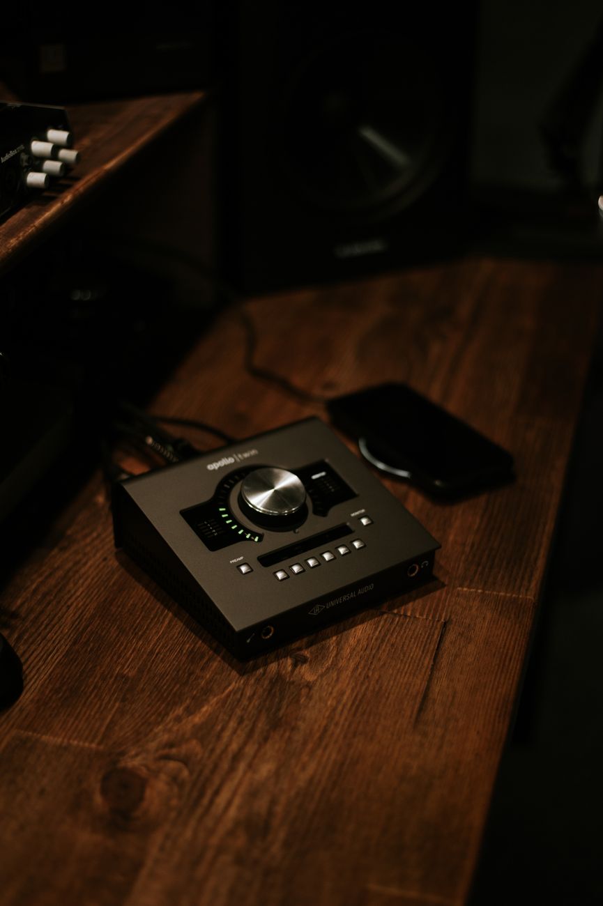 Dark, moody still life of a vintage audio interface on a wooden desk indoors.