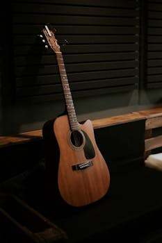 Wooden acoustic guitar in a dark, cozy studio setting, perfect for musical inspiration.