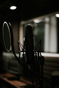 Close-up of a microphone in a moody recording studio setting, ideal for music production themes.