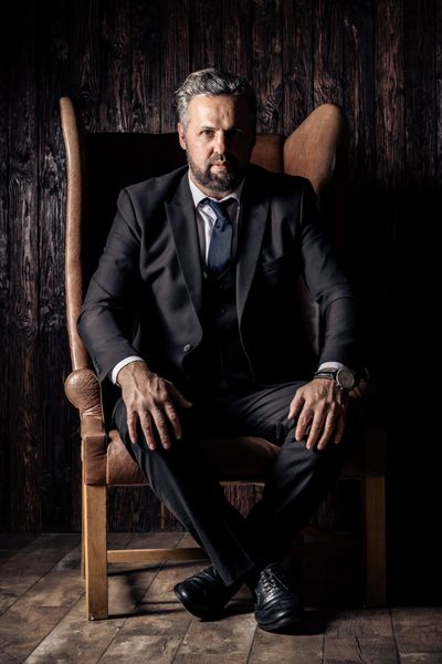 Man in a dark suit seated in a dim interior — photo by Alexa Popovich on Pexels