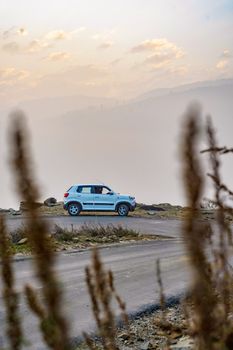 A lone SUV parked on a winding mountain road enveloped in fog and mystery.