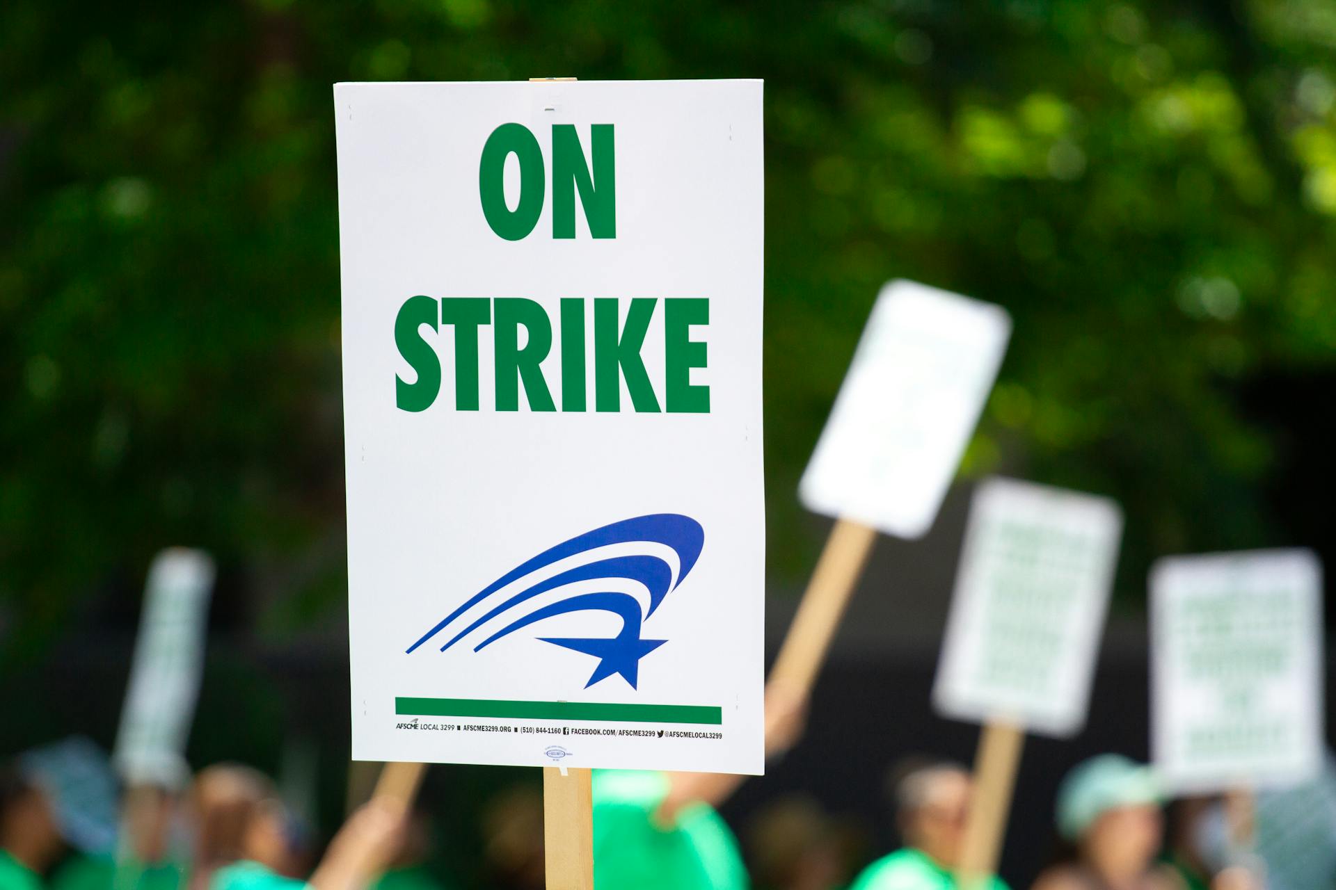 A protest sign with 'On Strike' text held during an outdoor demonstration, highlighting labor movements.