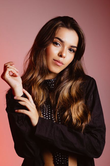 A confident young woman posing gracefully in a stylish fashion portrait with soft lighting.