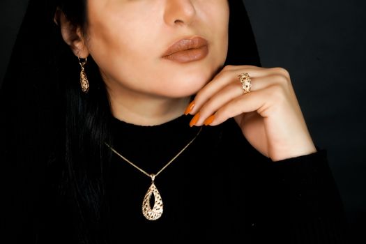 Close-up of a woman adorned in an elegant gold jewelry set, featuring a necklace, earrings, and ring.