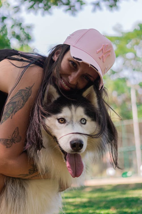 Woman Weairng Pink Cap Hugging a Dog