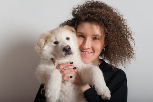 Free Woman with Curly Hair Carrying a White Dog Stock Photo