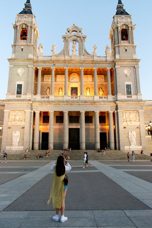 Symmetrical View of an Illuminated Cathedral and Woman in a Yellow Dress Photographing