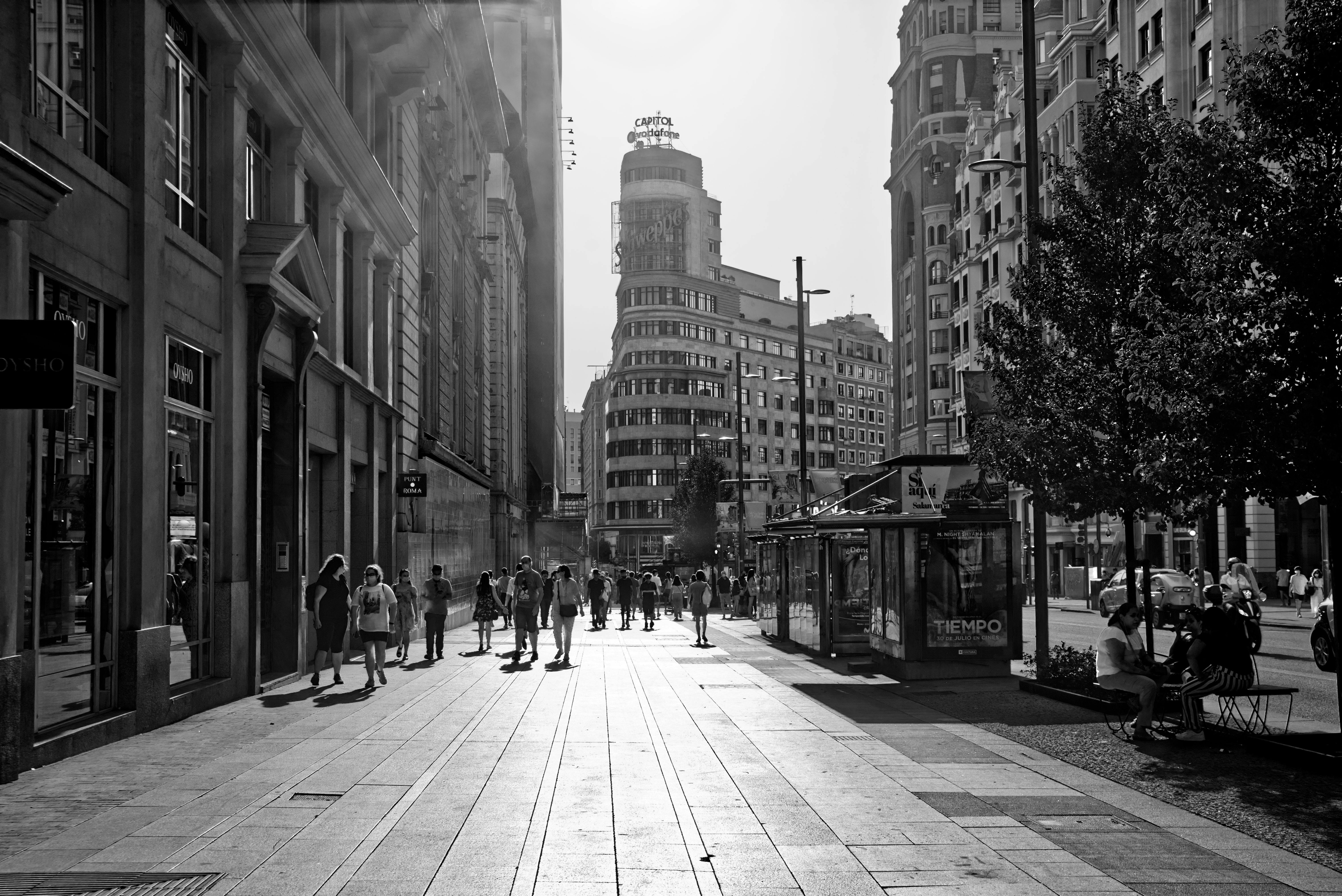 Monochrome view of Madrid's city street capturing lively pedestrian activity.