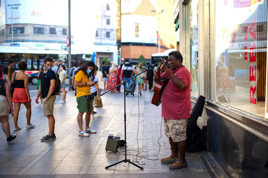 Un artista callejero toca la guitarra para los transeúntes en el bullicioso centro de Madrid.