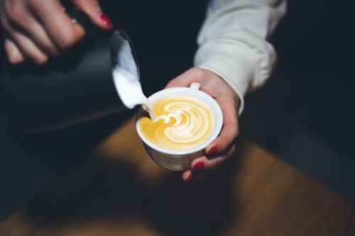 Free Close-up of latte art being poured with creamy milk into espresso, perfect for coffee enthusiasts. Stock Photo