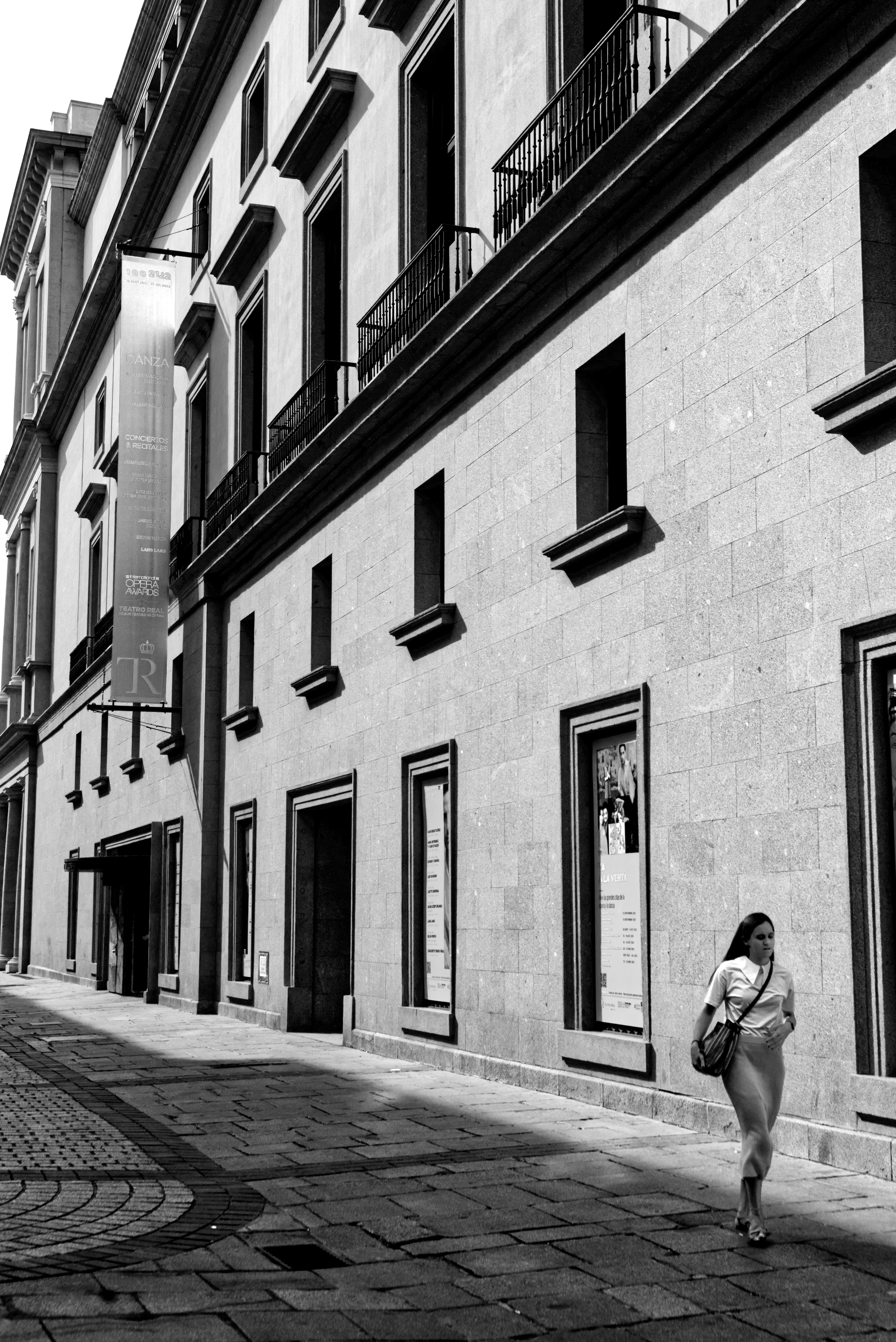 A Grayscale of a Woman Walking on a Sidewalk · Free Stock Photo