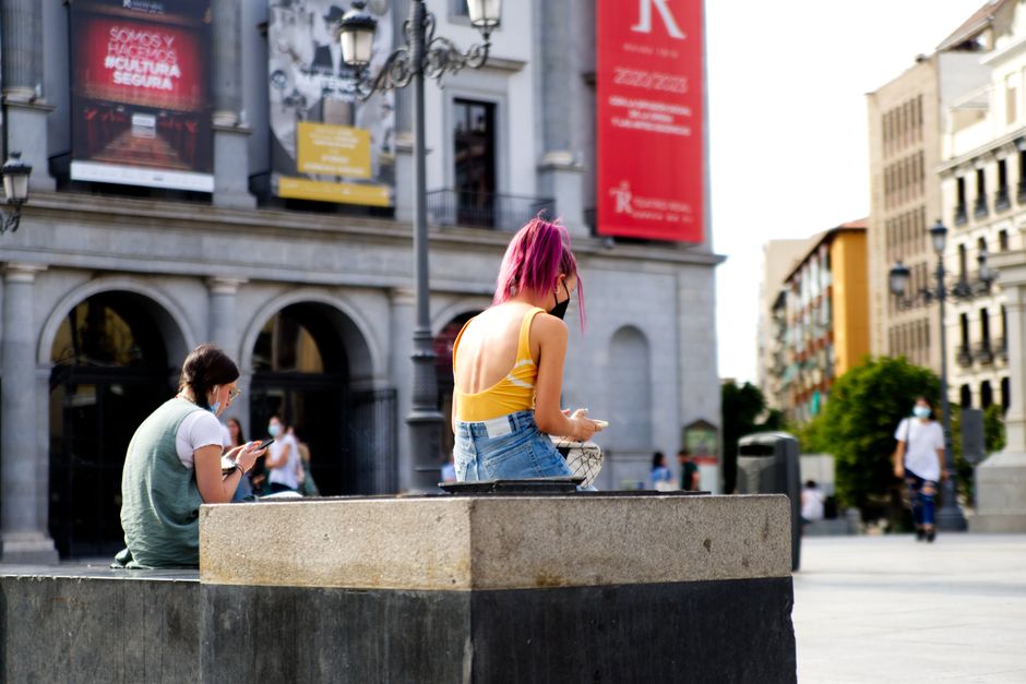 Escena urbana en Madrid con personas usando mascarillas, reflejando la vida moderna de la ciudad.