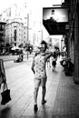 Grayscale Photo of Man Walking on Sidewalk