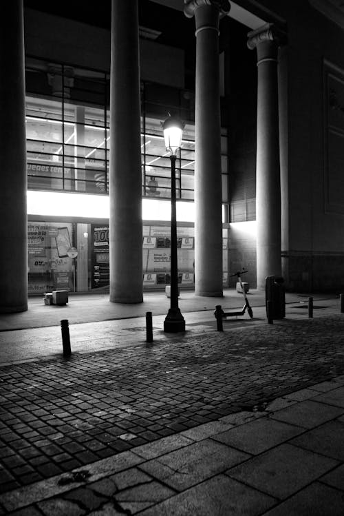 

A Grayscale of a Street Lamp Illuminating a Road at Night